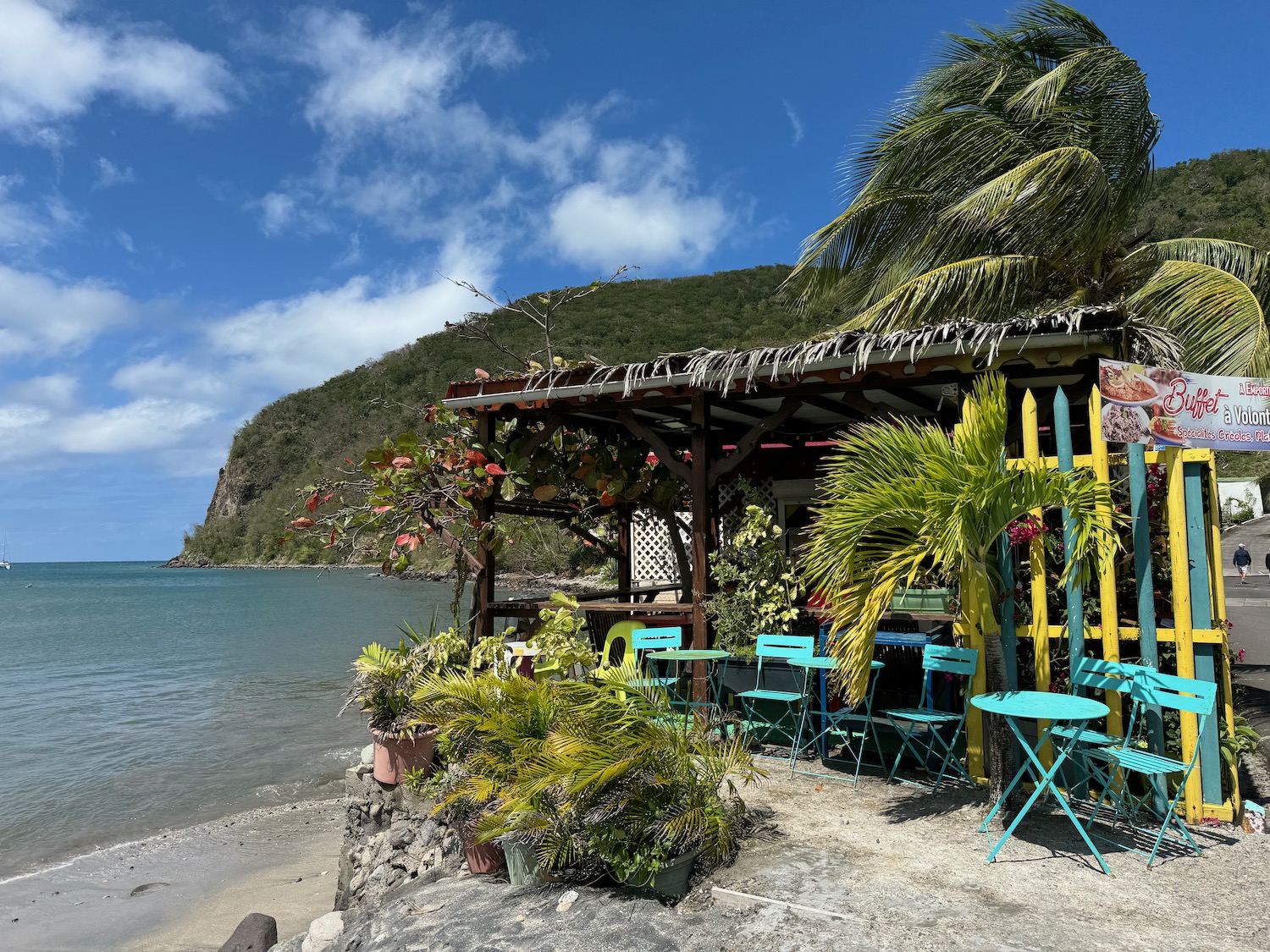 a beach with a hut and chairs and a beach with a mountain in the background