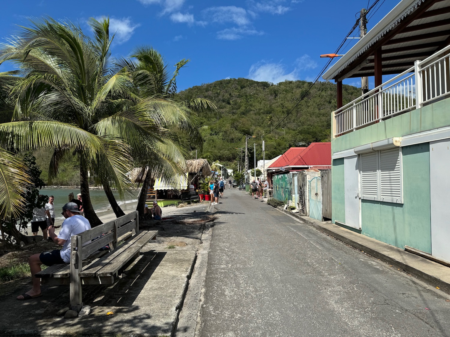 a street with a bench and buildings and a body of water