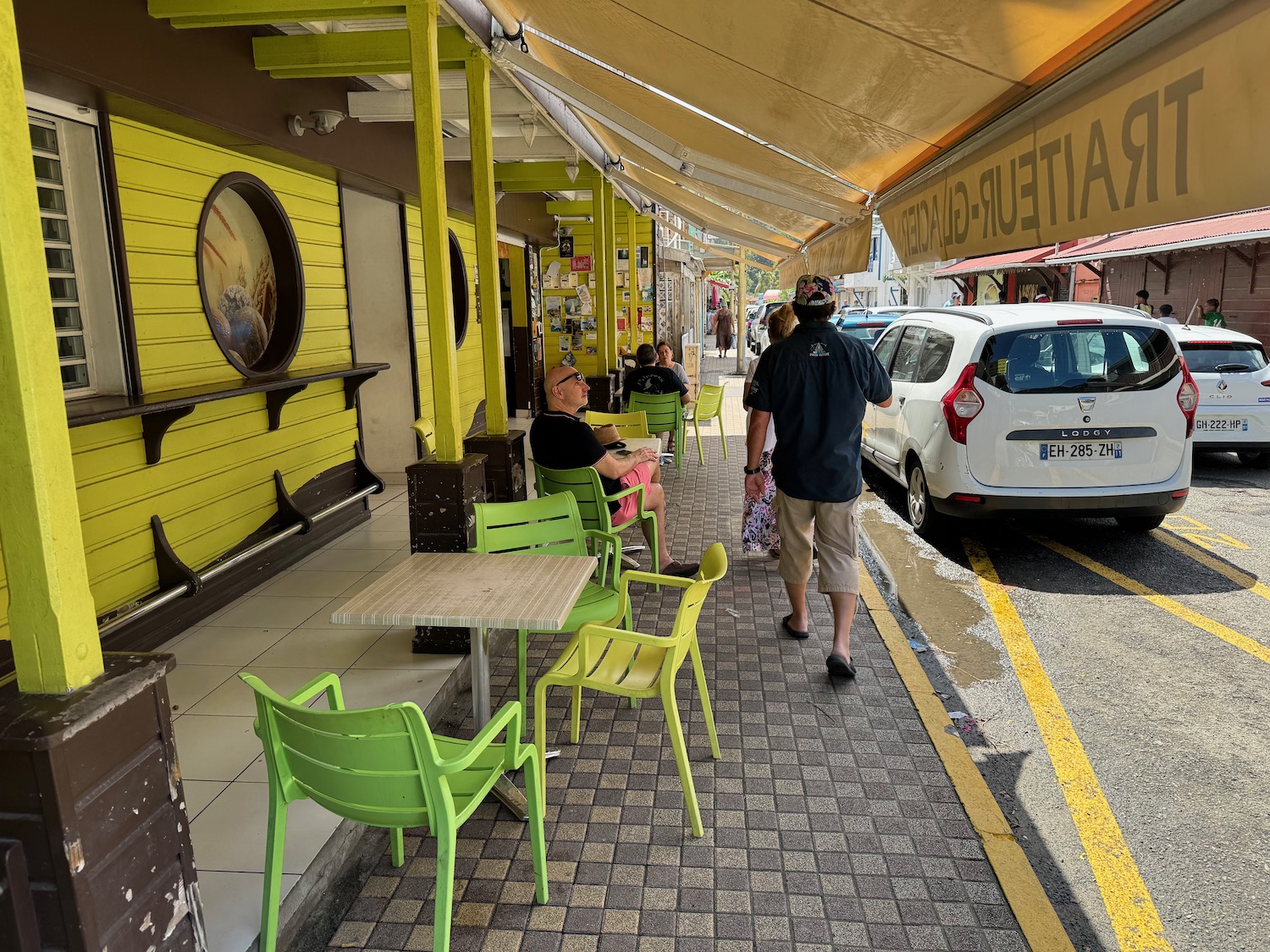 people sitting on a sidewalk with tables and chairs