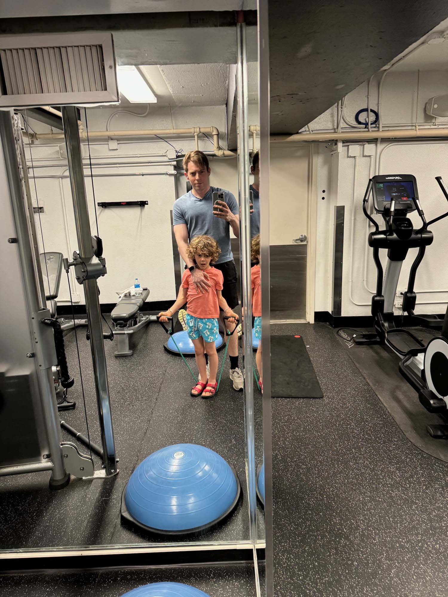 a man taking a selfie with two children in a gym
