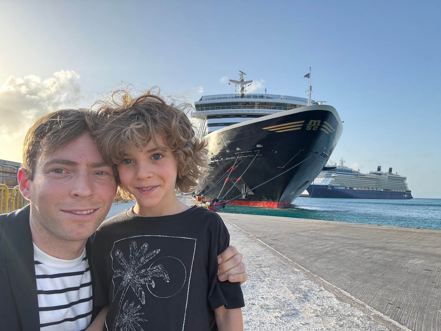 a man and boy posing for a picture in front of a large ship