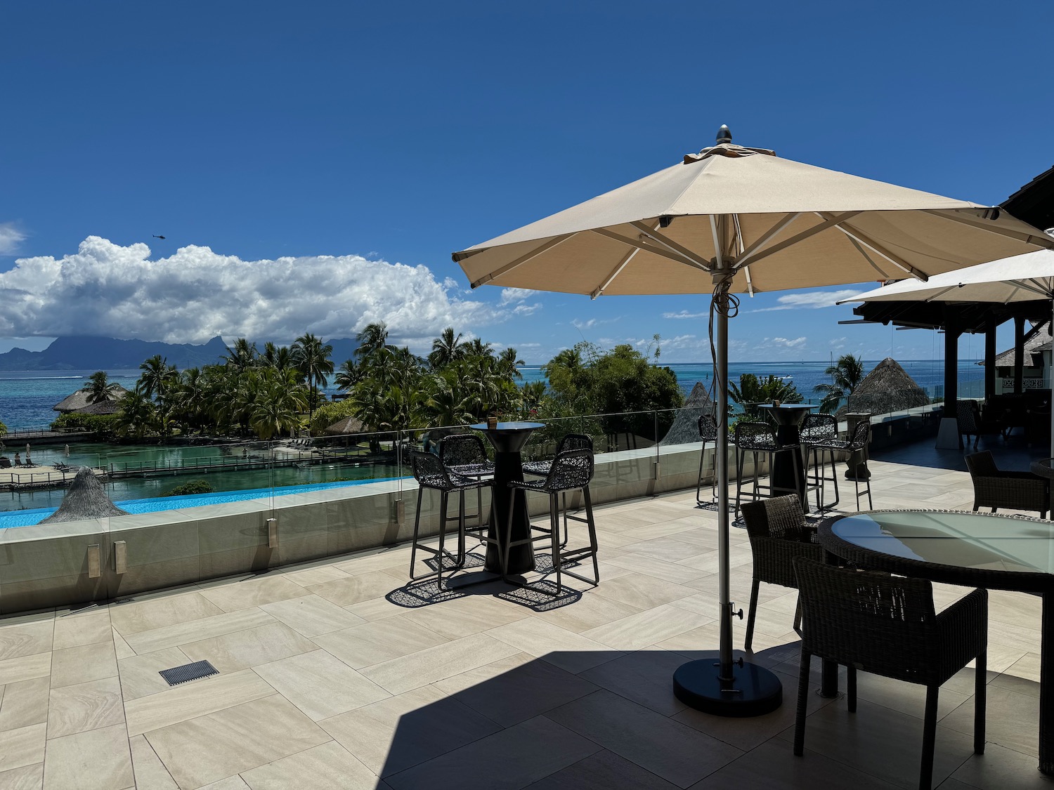 a patio with chairs and umbrellas and a pool in the background