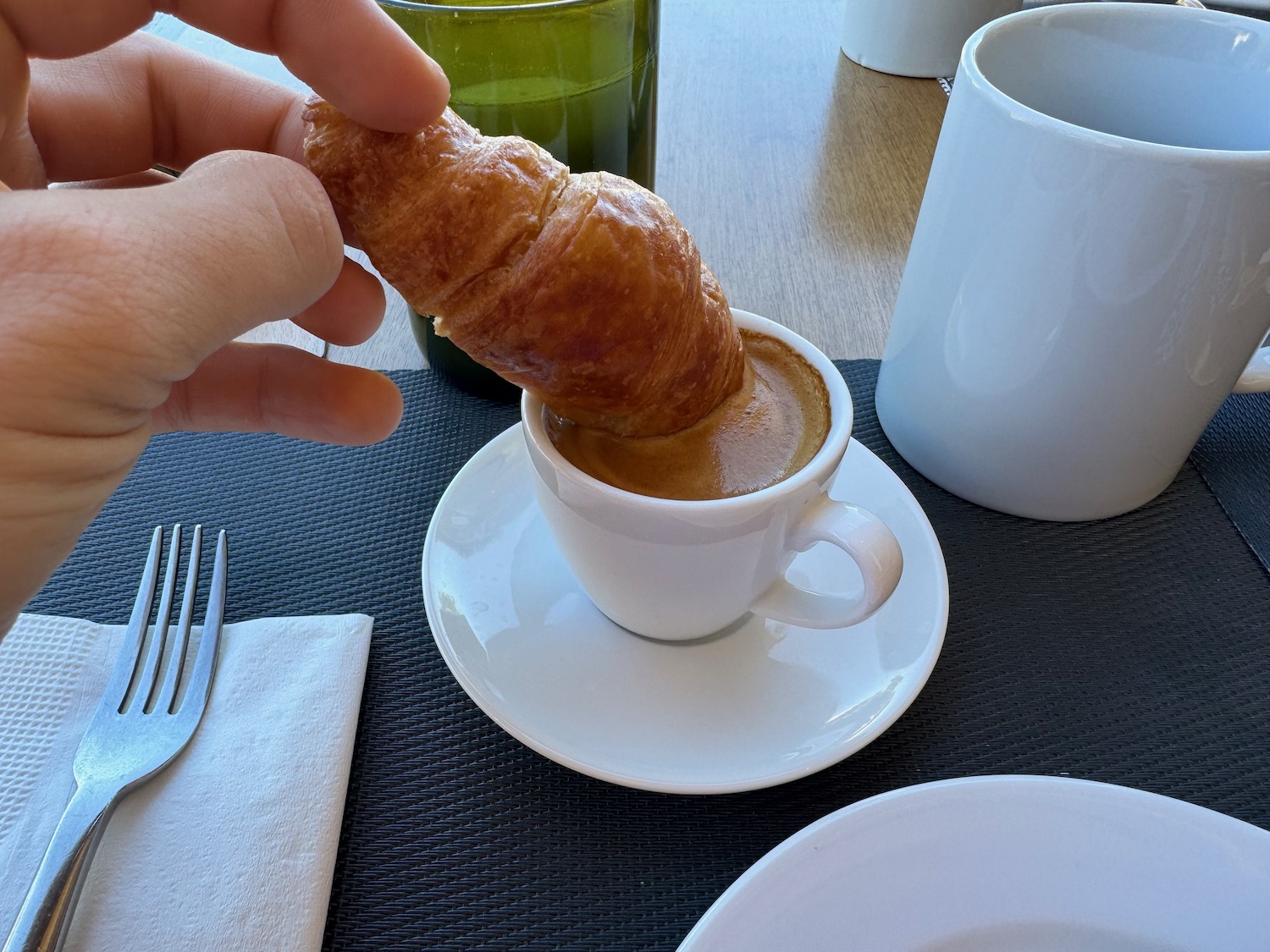 a croissant being dipped into a cup of coffee