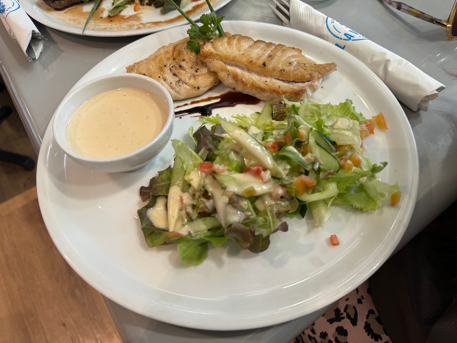 a plate of food with sauce and a bowl of salad