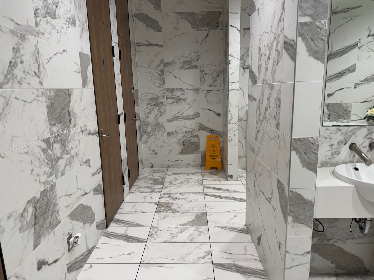 a bathroom with marble tiles and a yellow sign