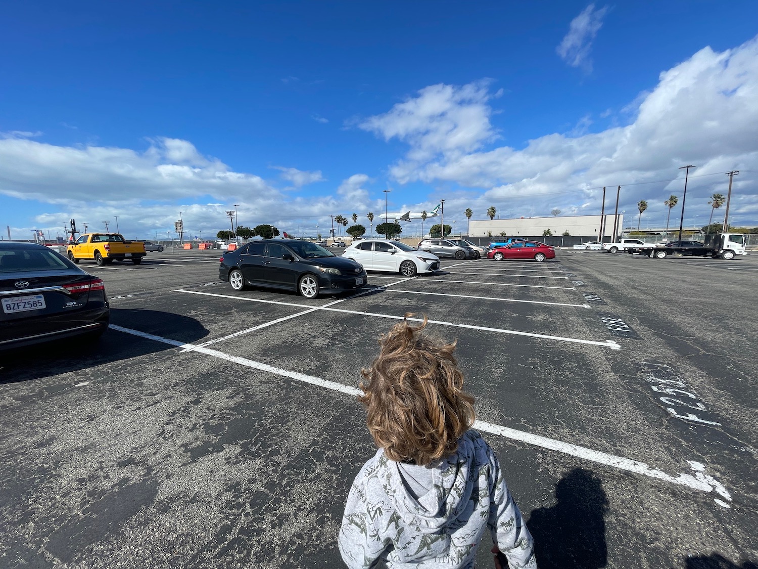 a child standing in a parking lot with cars