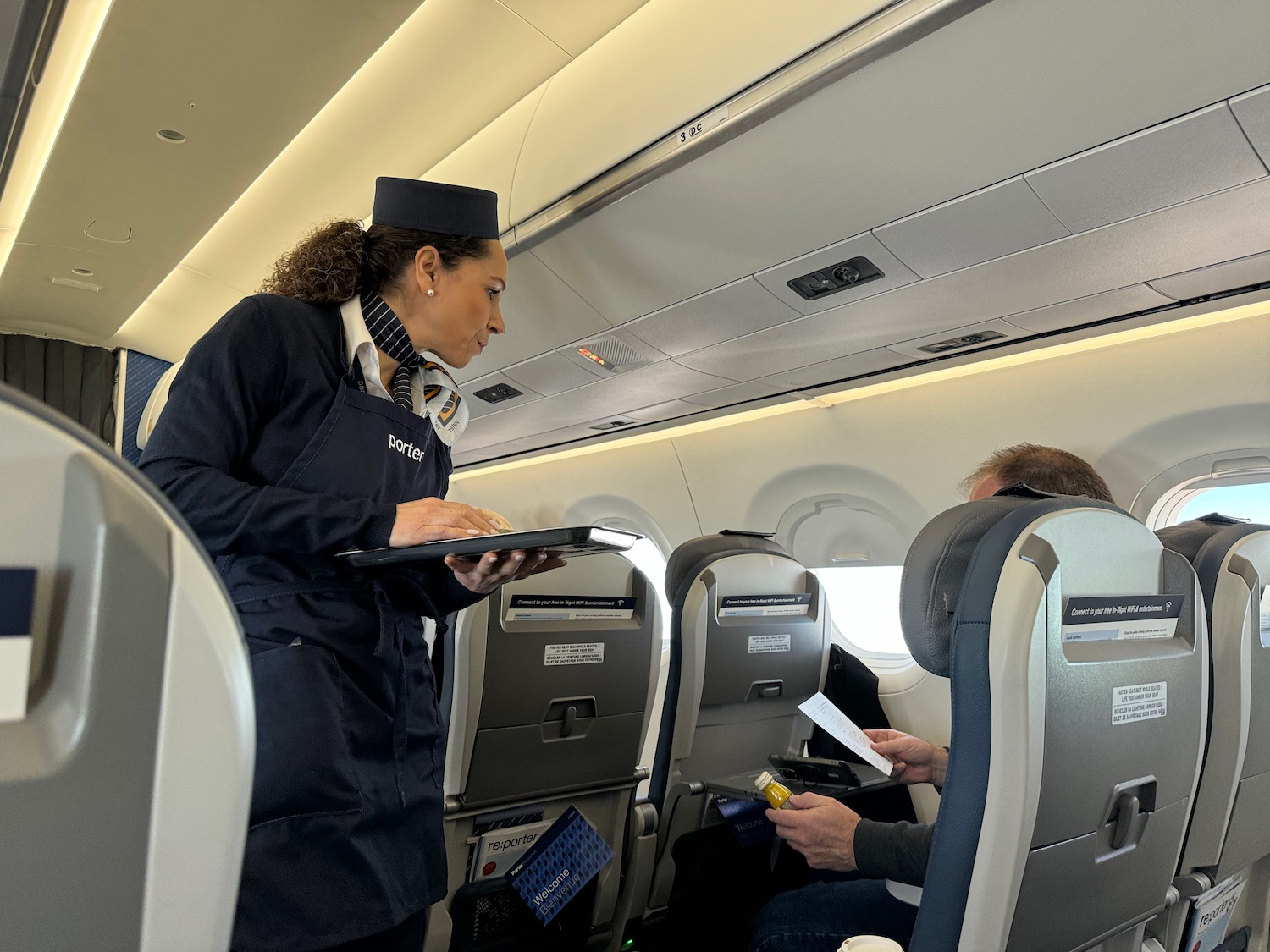 a woman in a uniform serving a man in an airplane