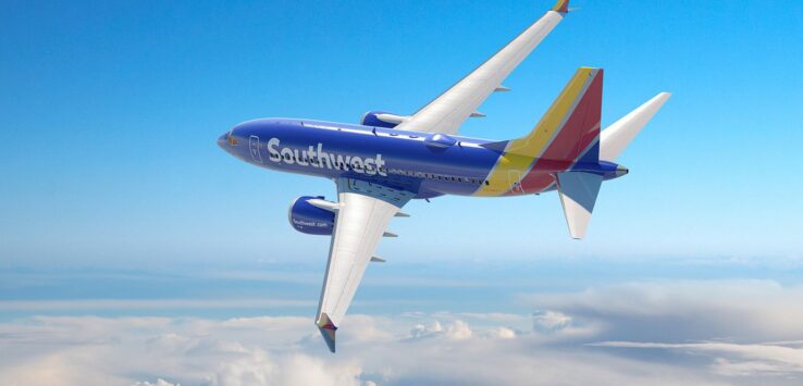 a blue and yellow airplane in the sky