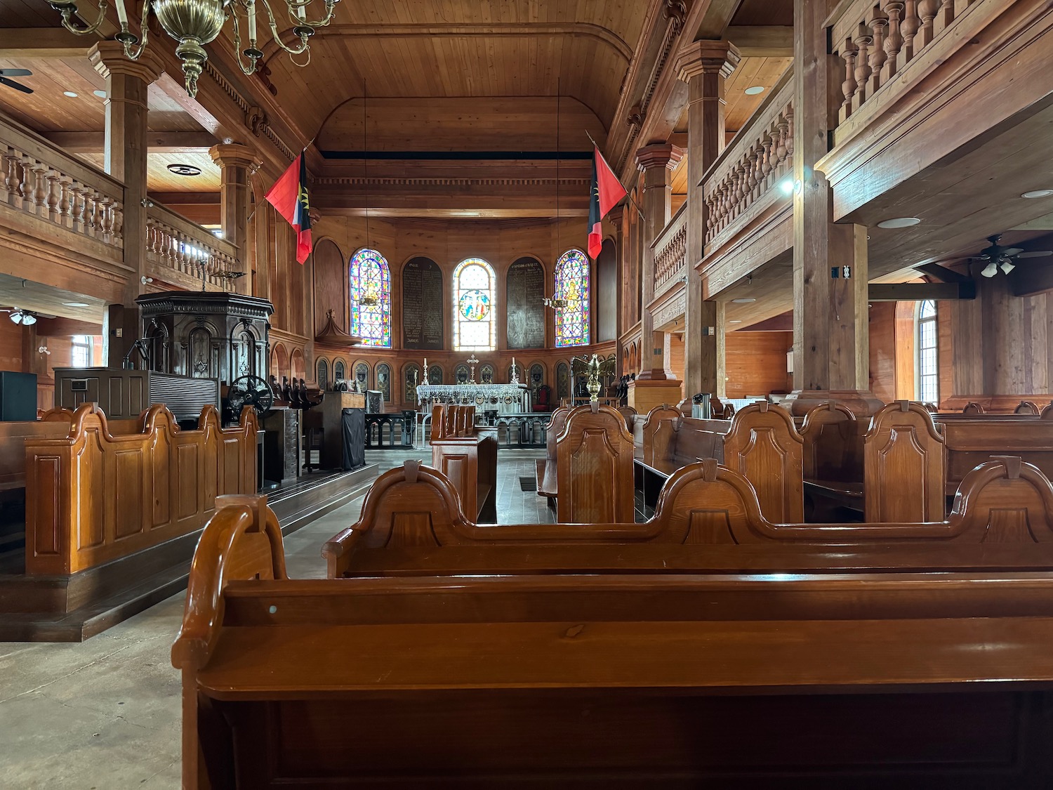 inside a church with wood benches and a chandelier