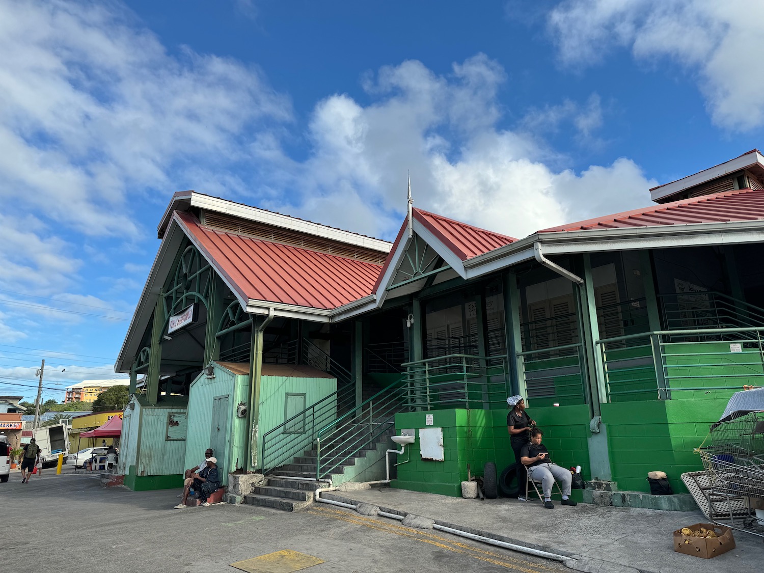 a building with a green wall and a man sitting on a bench