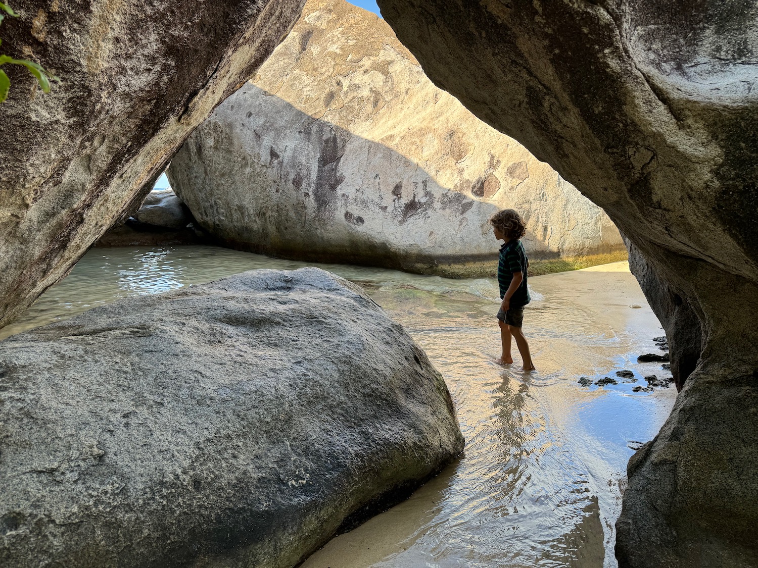 a child standing in water near large rocks