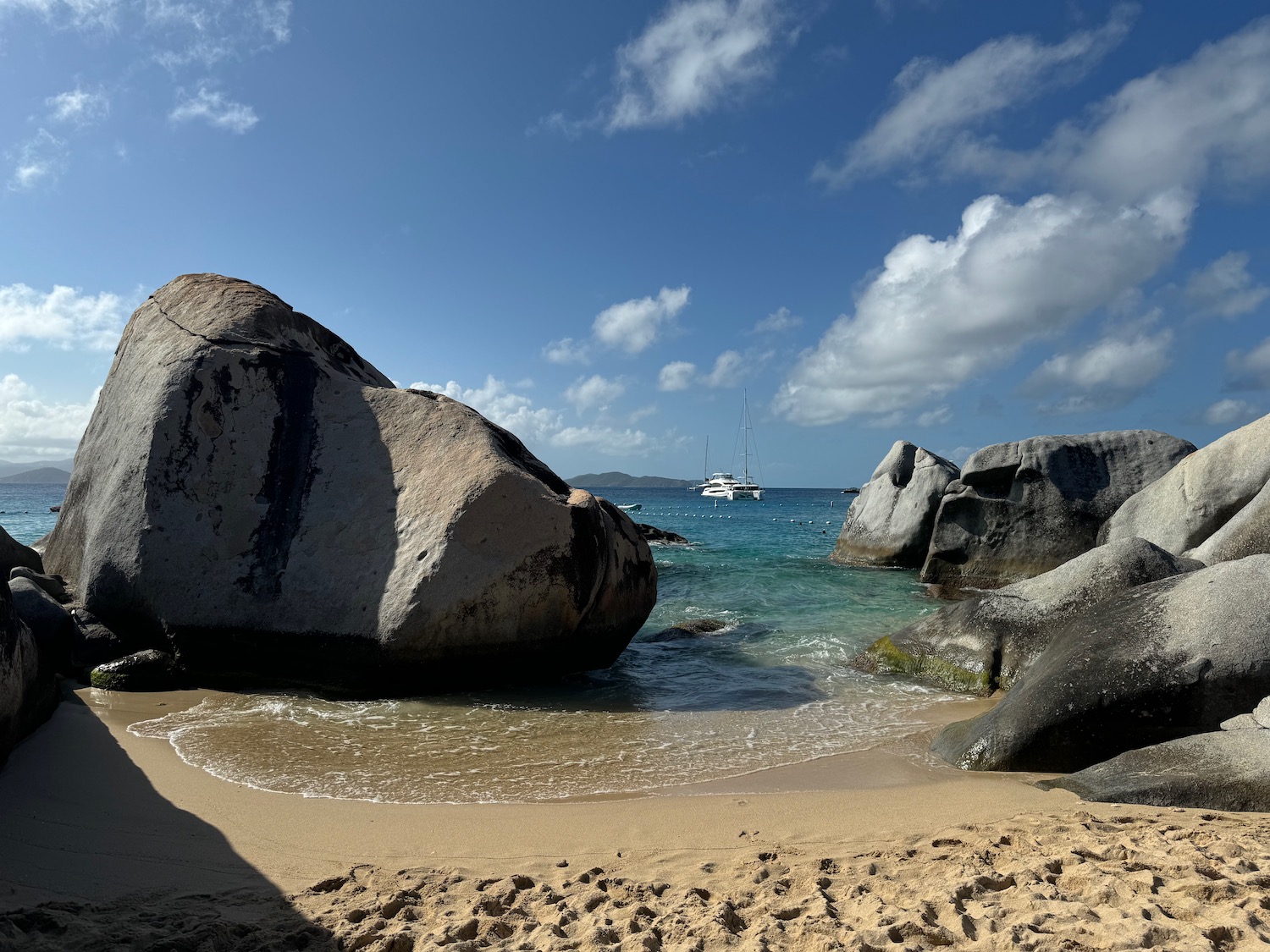 a beach with large rocks and a boat