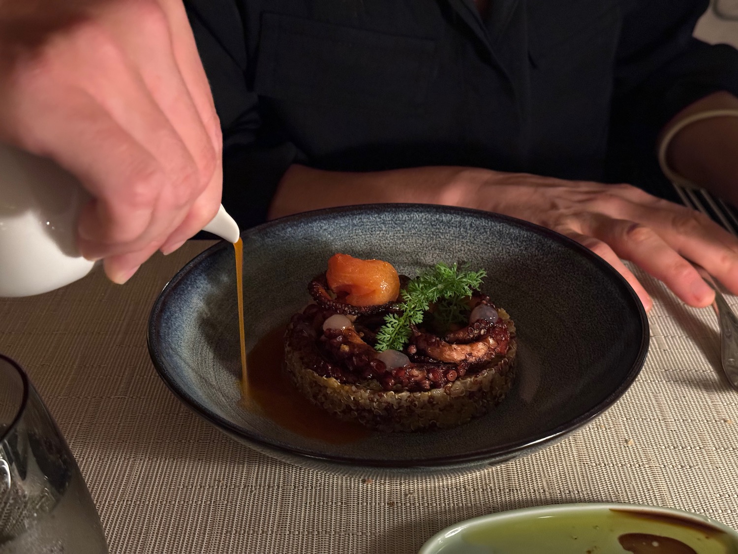 a person pouring liquid onto a plate of food