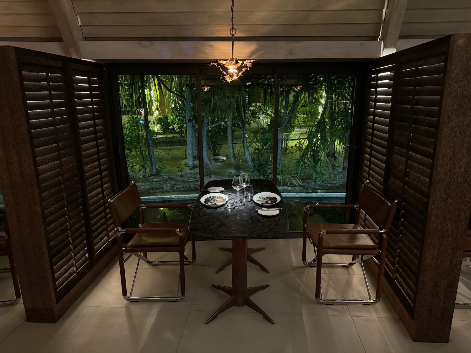 a table with plates and chairs in a room with a window