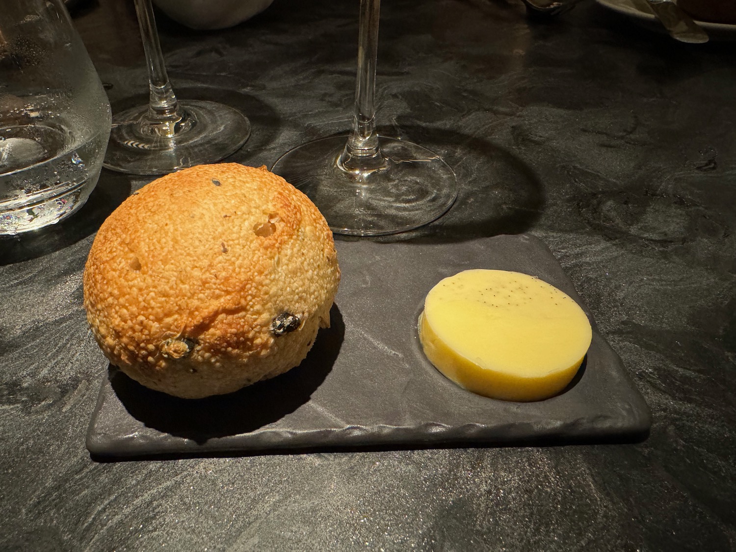 a round bread and a slice of potato on a black plate