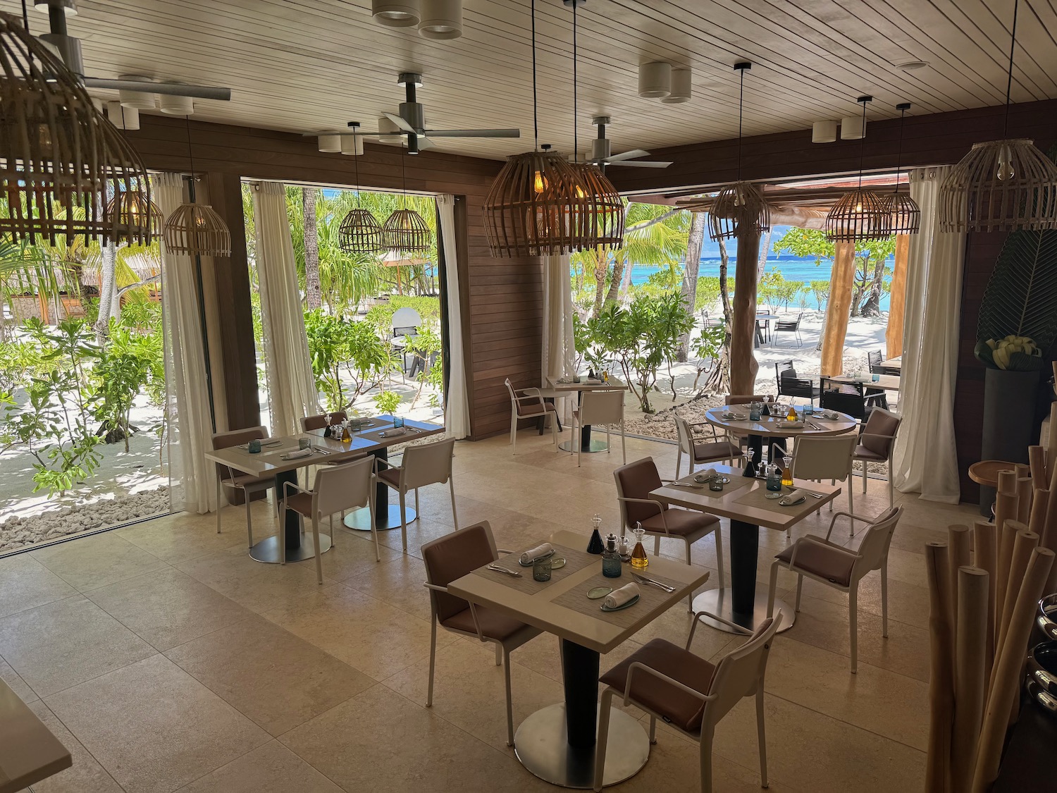 a room with tables and chairs and a view of the ocean