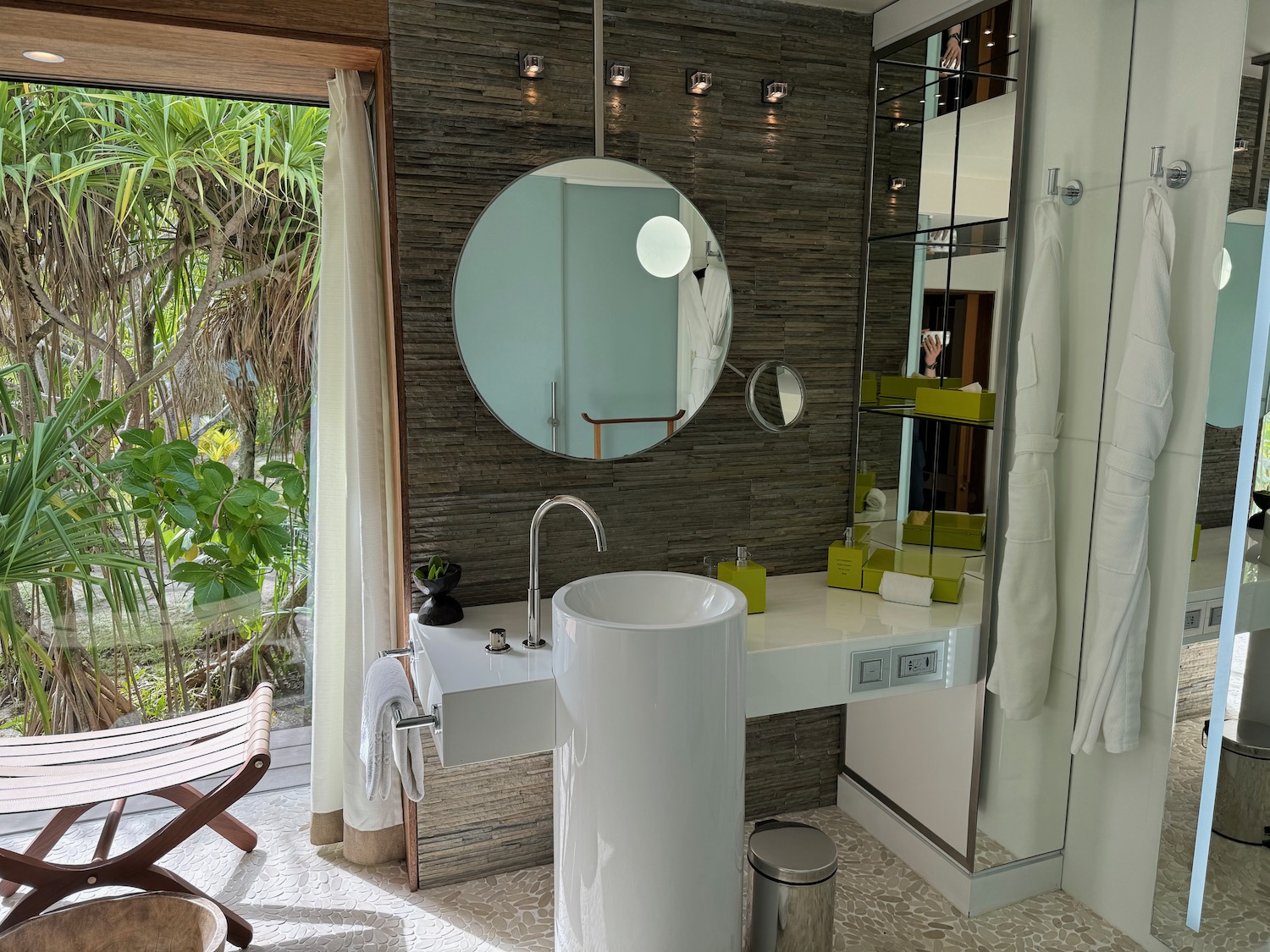 a bathroom with a round mirror and sink