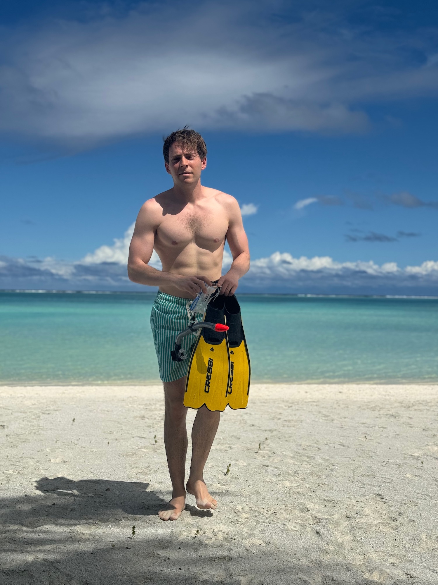 a man holding a yellow flippers on a beach