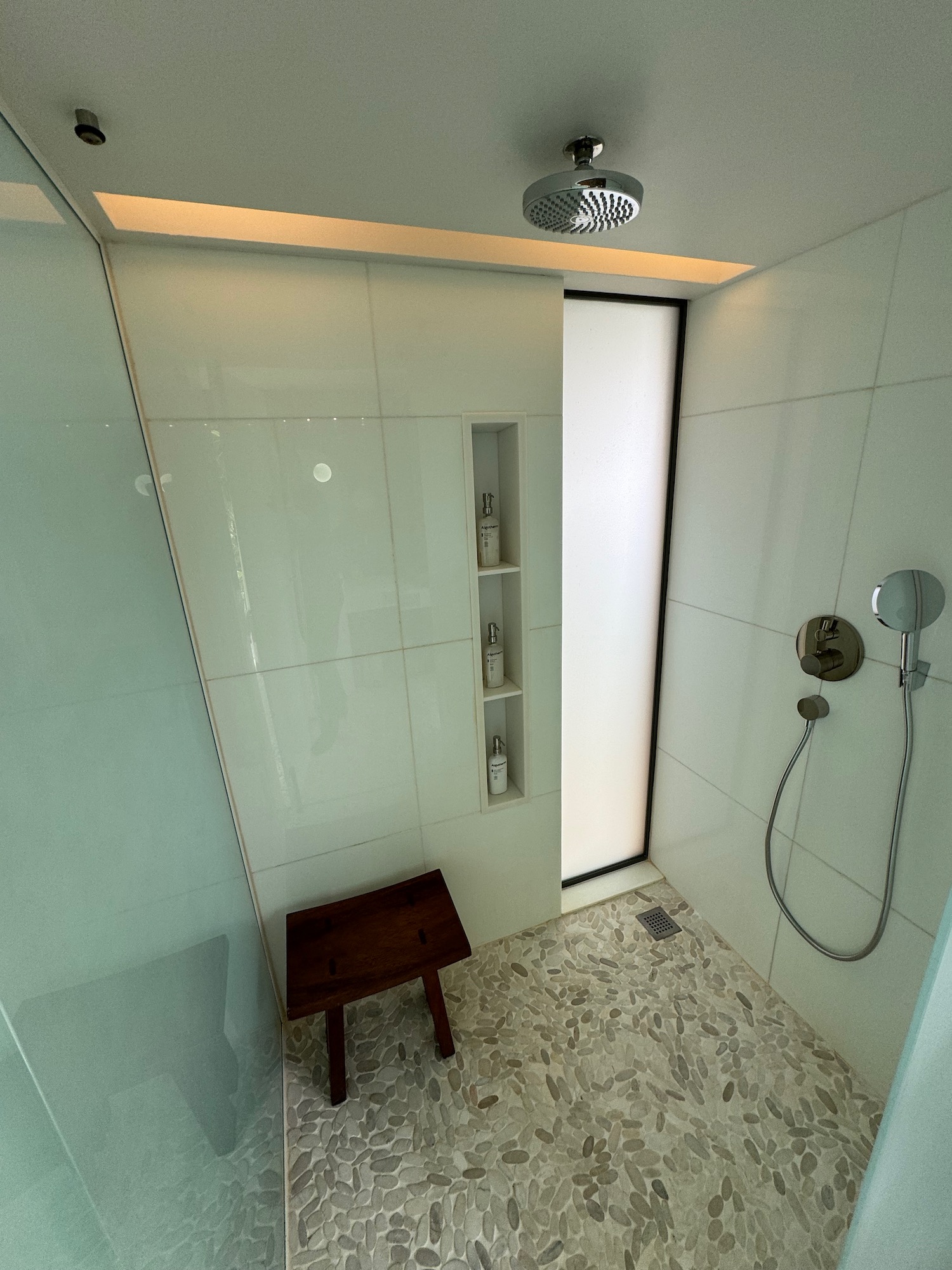 a shower with a shower head and a small bench