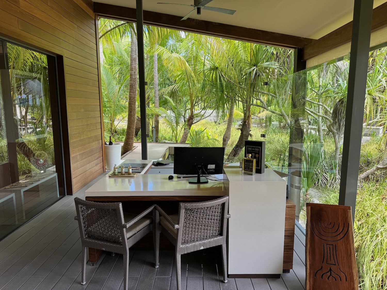 a desk with chairs and a computer in a room with trees in the background