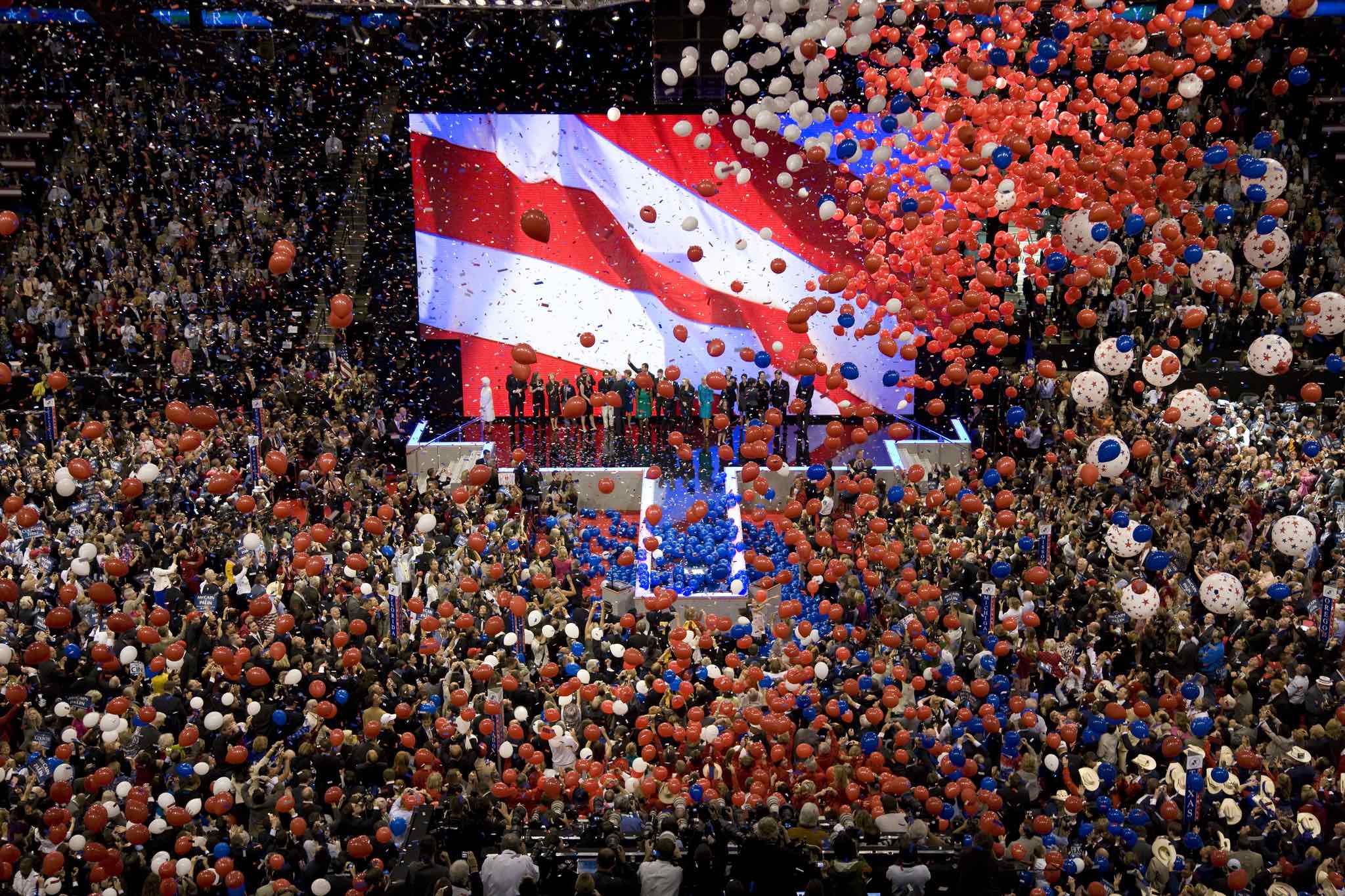 a large crowd of people in a stadium with balloons flying in the air