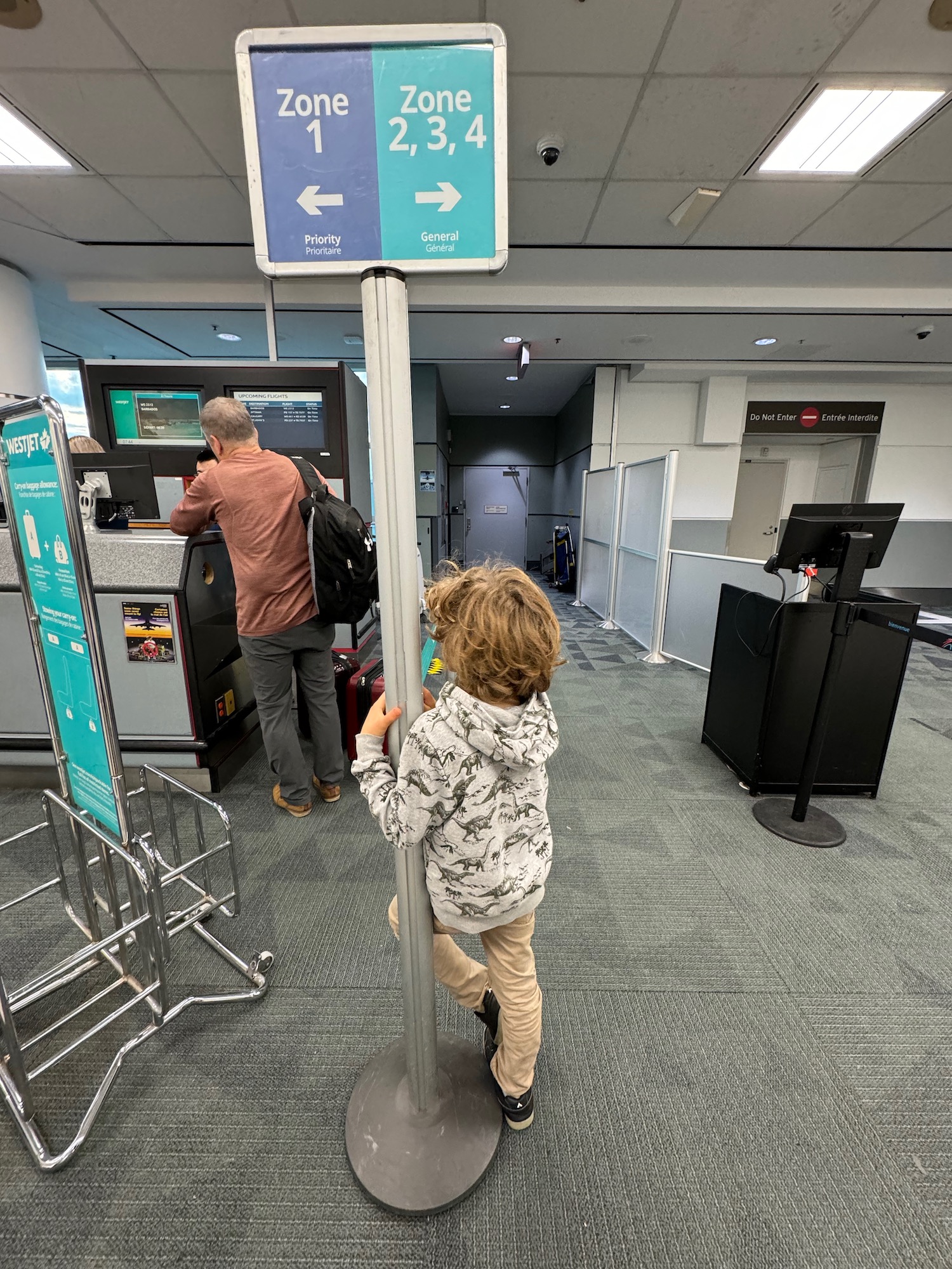 a child standing next to a man at an airport check in machine