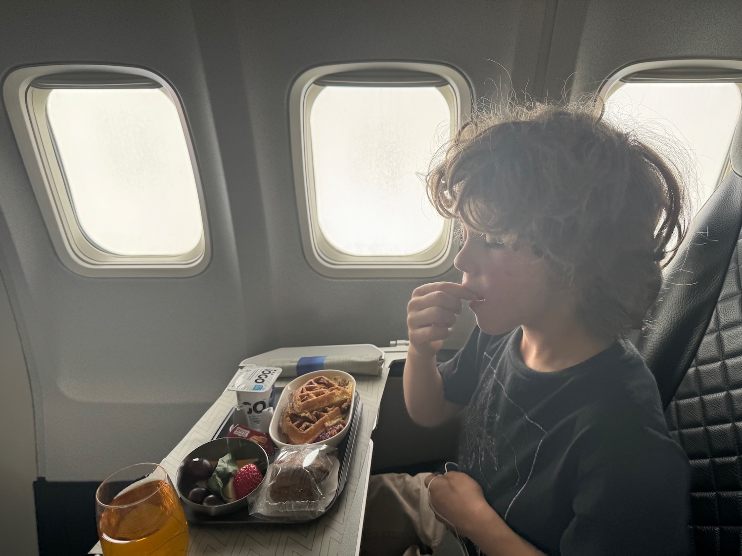 a boy eating food on an airplane