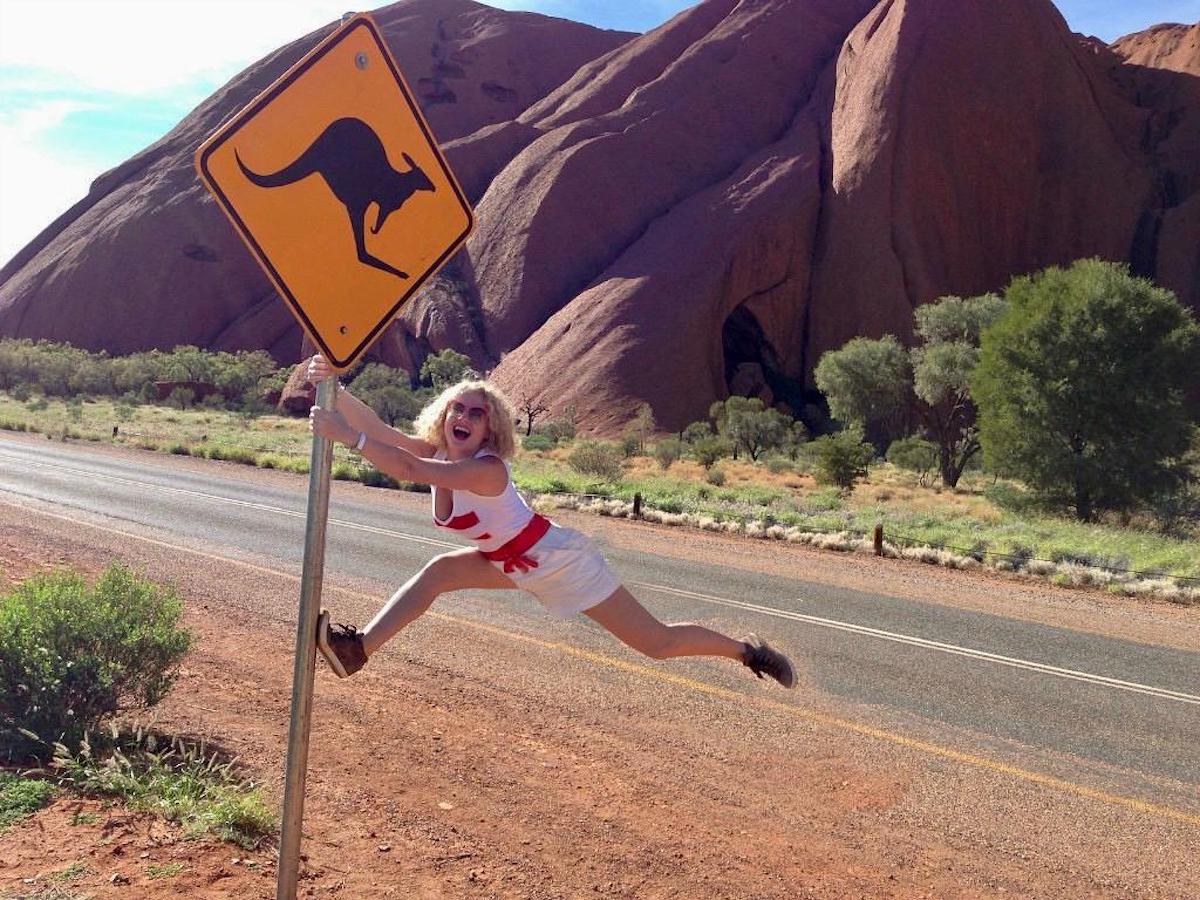 a woman jumping on a sign