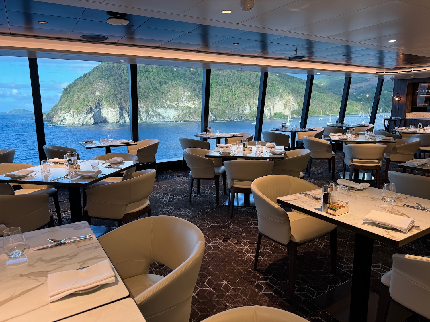 a restaurant with tables and chairs and a view of the ocean