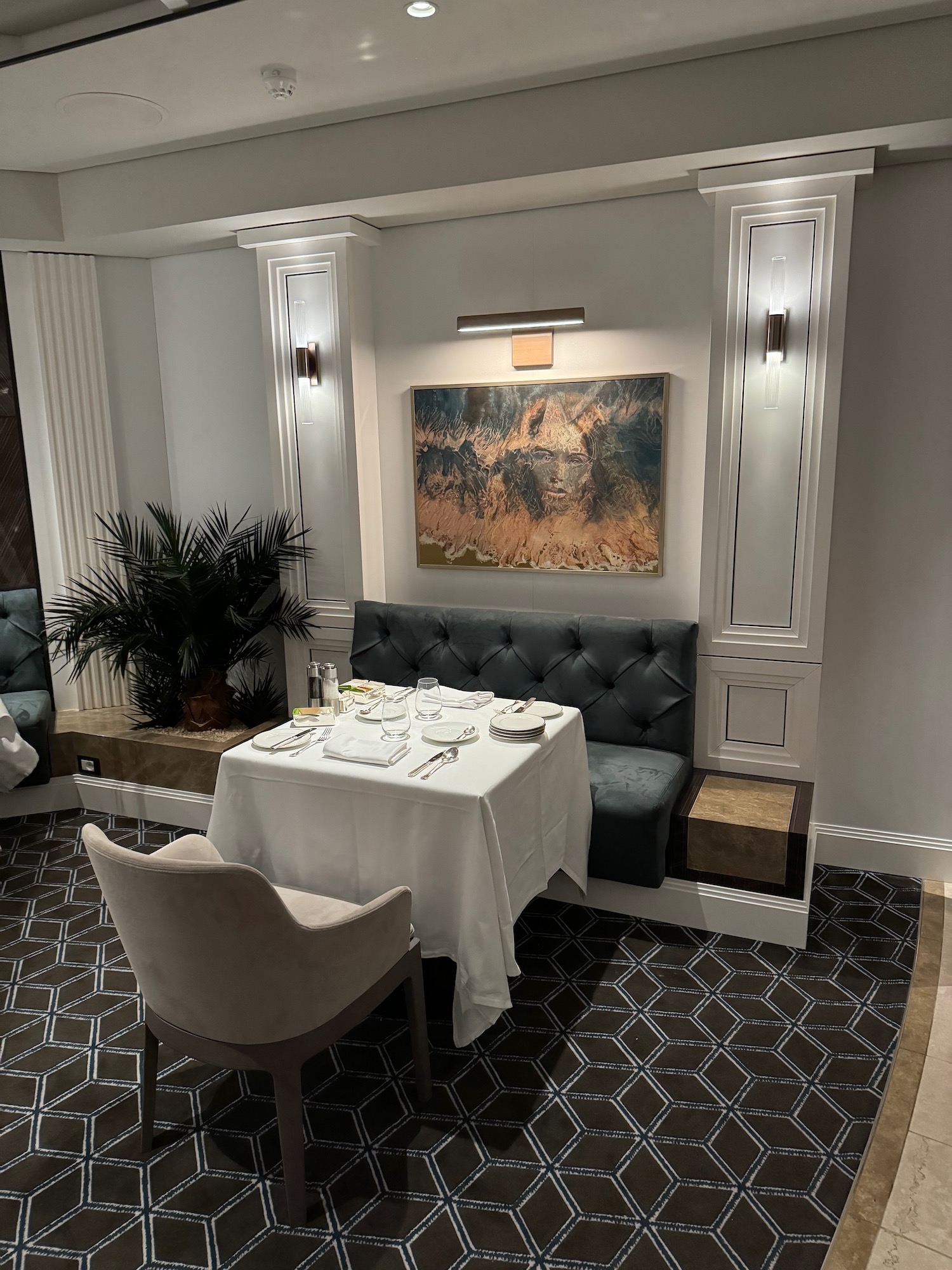 a table with a white tablecloth and a painting on the wall