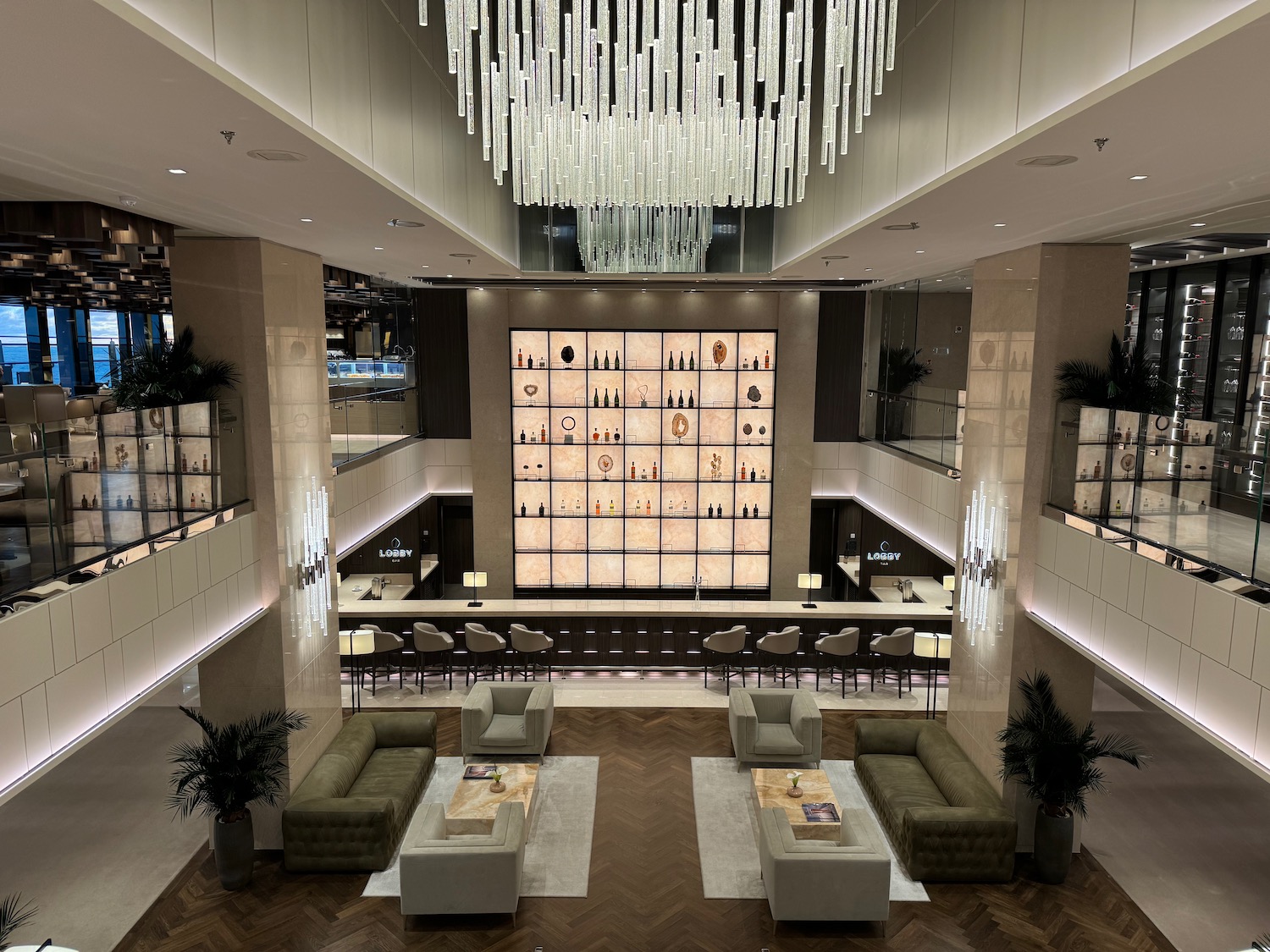 a room with a chandelier and a large wall with shelves and chairs