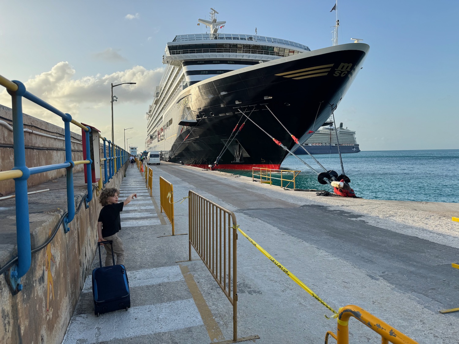 a boy standing on a dock next to a large cruise ship