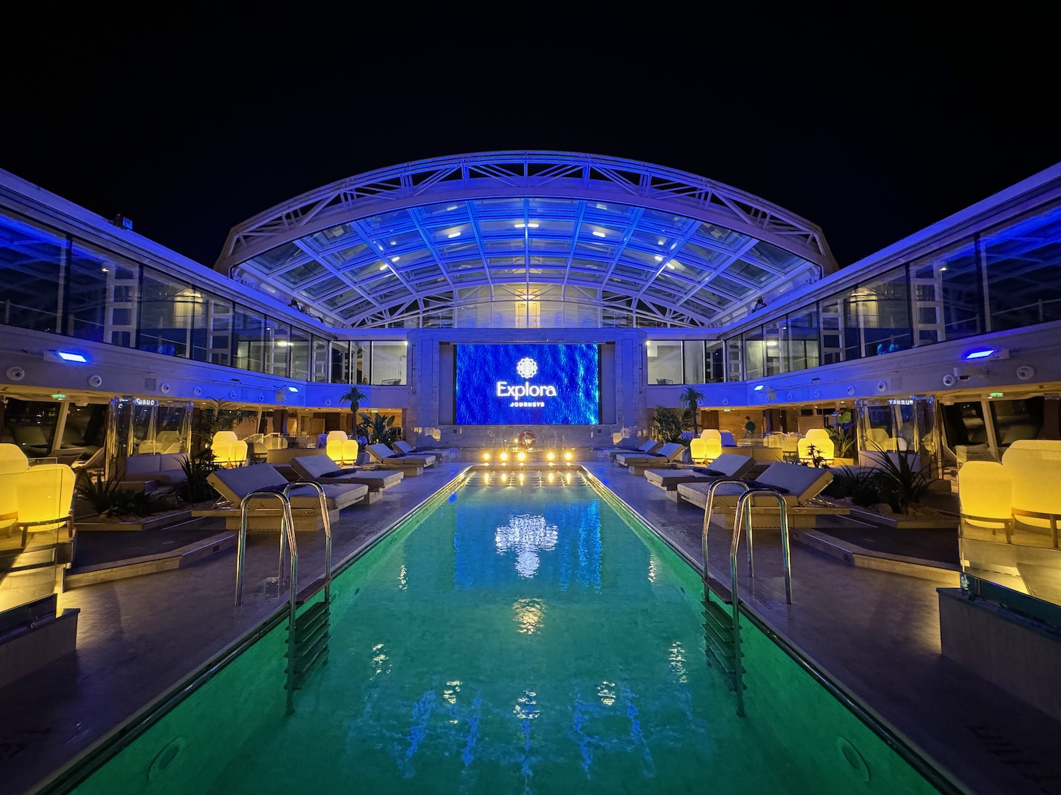 a pool with lounge chairs and a large building with a sign