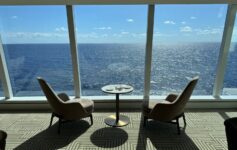 a room with chairs and a table overlooking the ocean