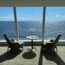 a room with chairs and a table overlooking the ocean