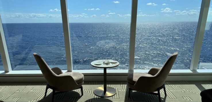 a room with chairs and a table overlooking the ocean