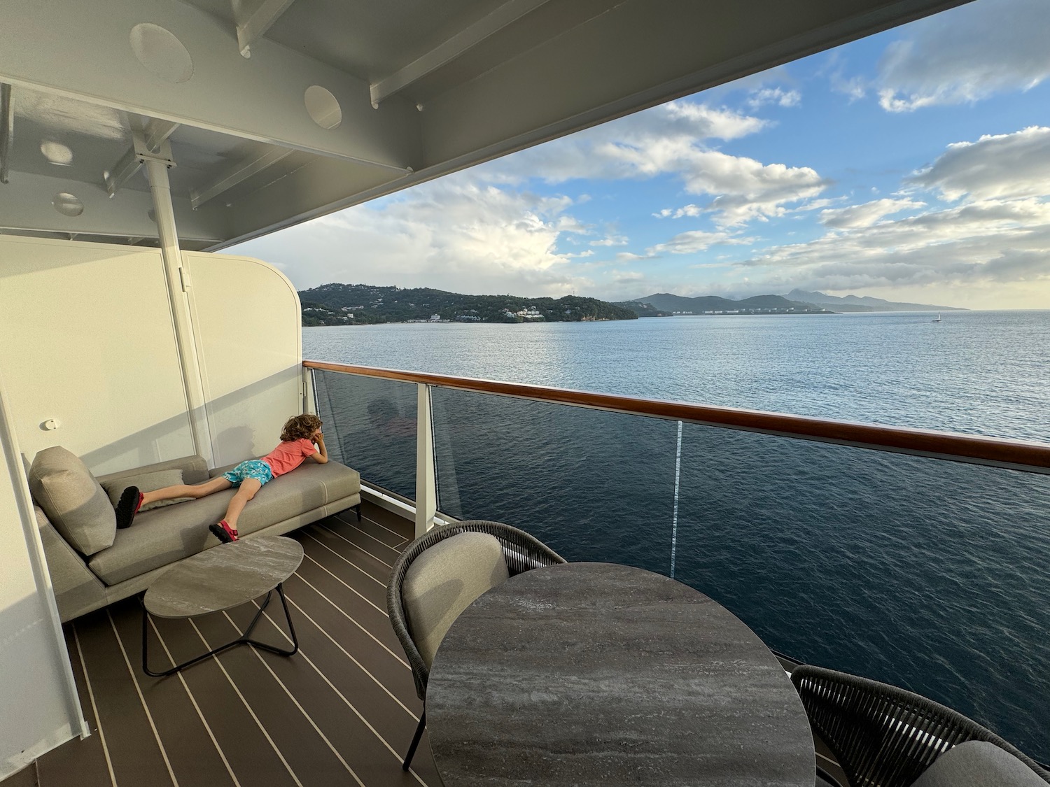 a child lying on a couch on a deck overlooking a body of water