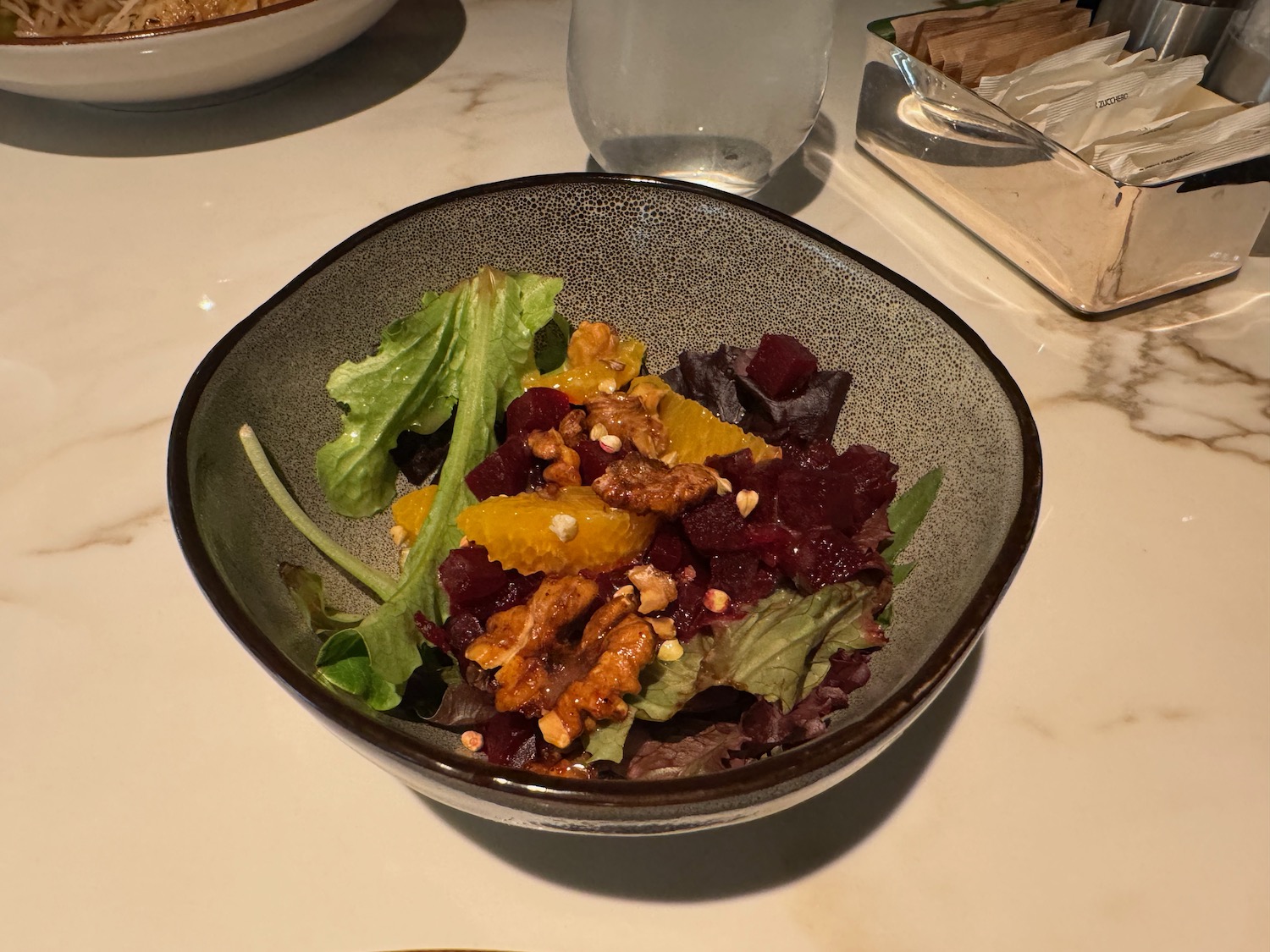 a bowl of salad with oranges and walnuts