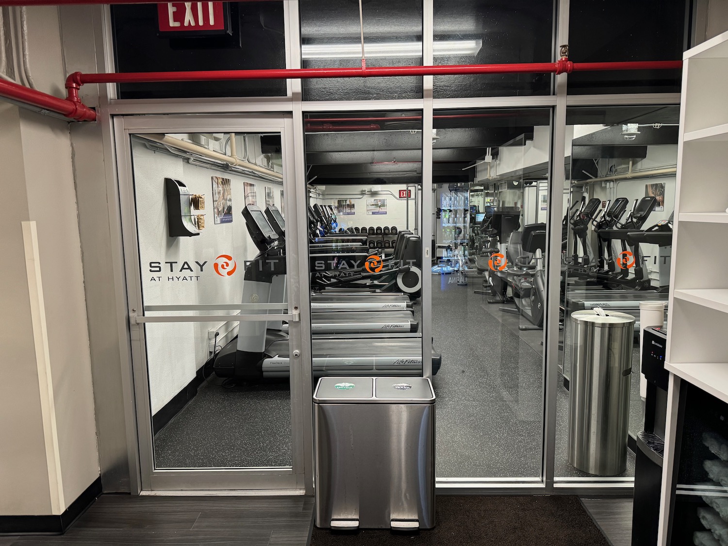 a gym with a door and a trash can