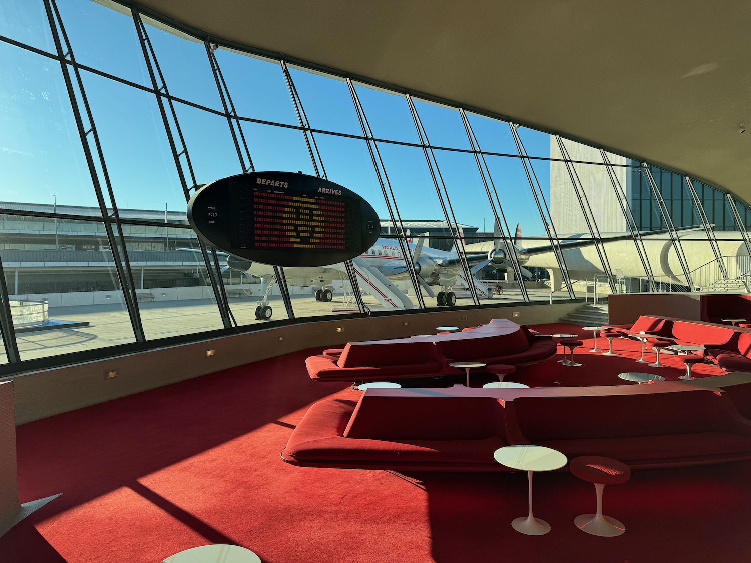 a lounge area with red couches and tables and a large window