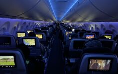 a row of seats with monitors on the back of the plane