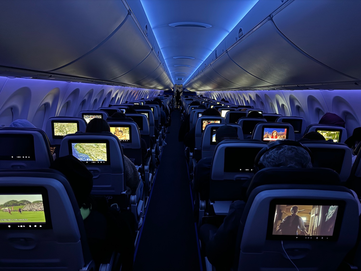 a row of seats with monitors on the back of the plane