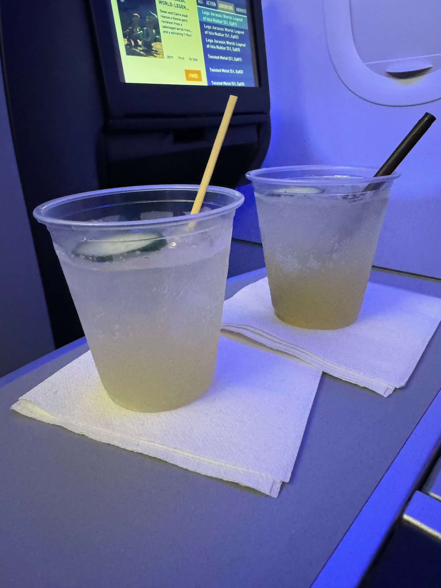 two cups of liquid with straws on a table