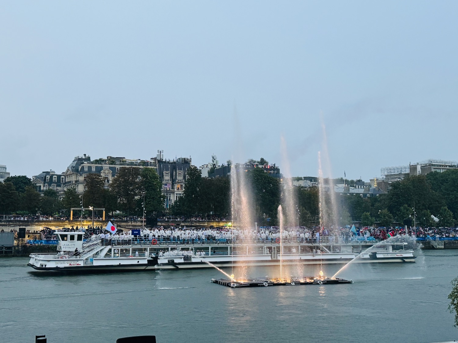 a large crowd of people on a boat with a fountain in the water