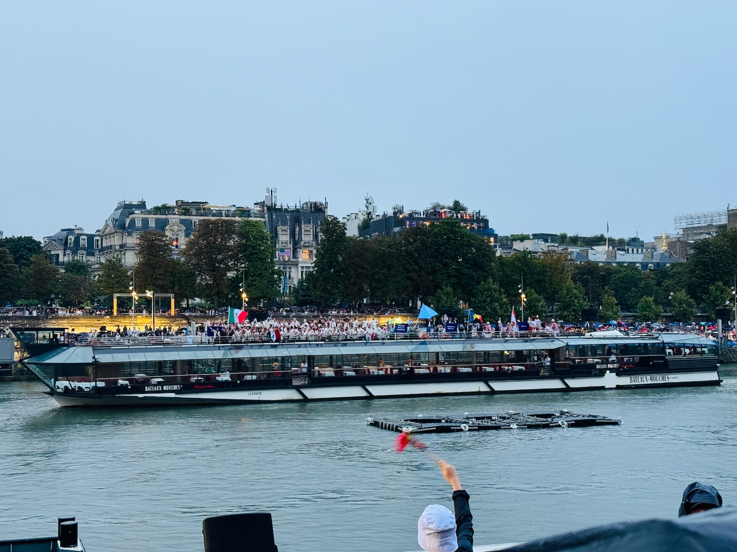 a person in a white hat on a boat with a crowd of people in the background