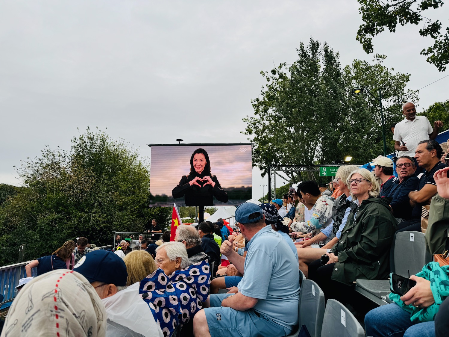 a crowd of people watching a woman on a screen