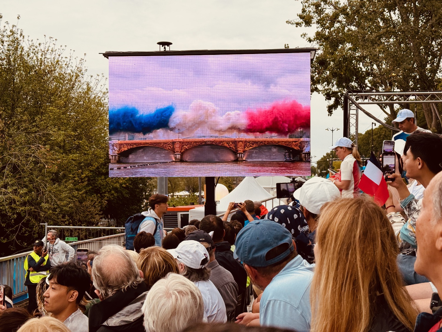 a group of people standing in a crowd watching a screen