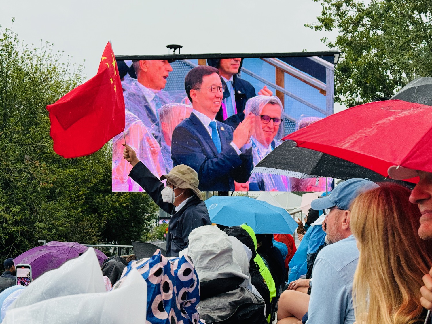 a group of people standing in a crowd holding a flag