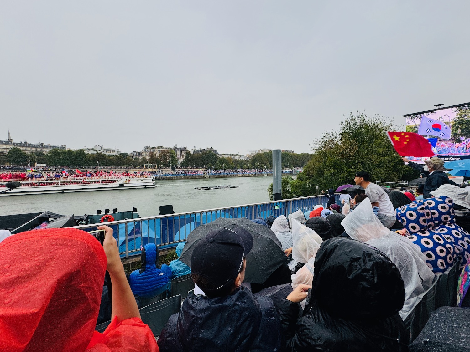 a group of people in raincoats watching a boat race