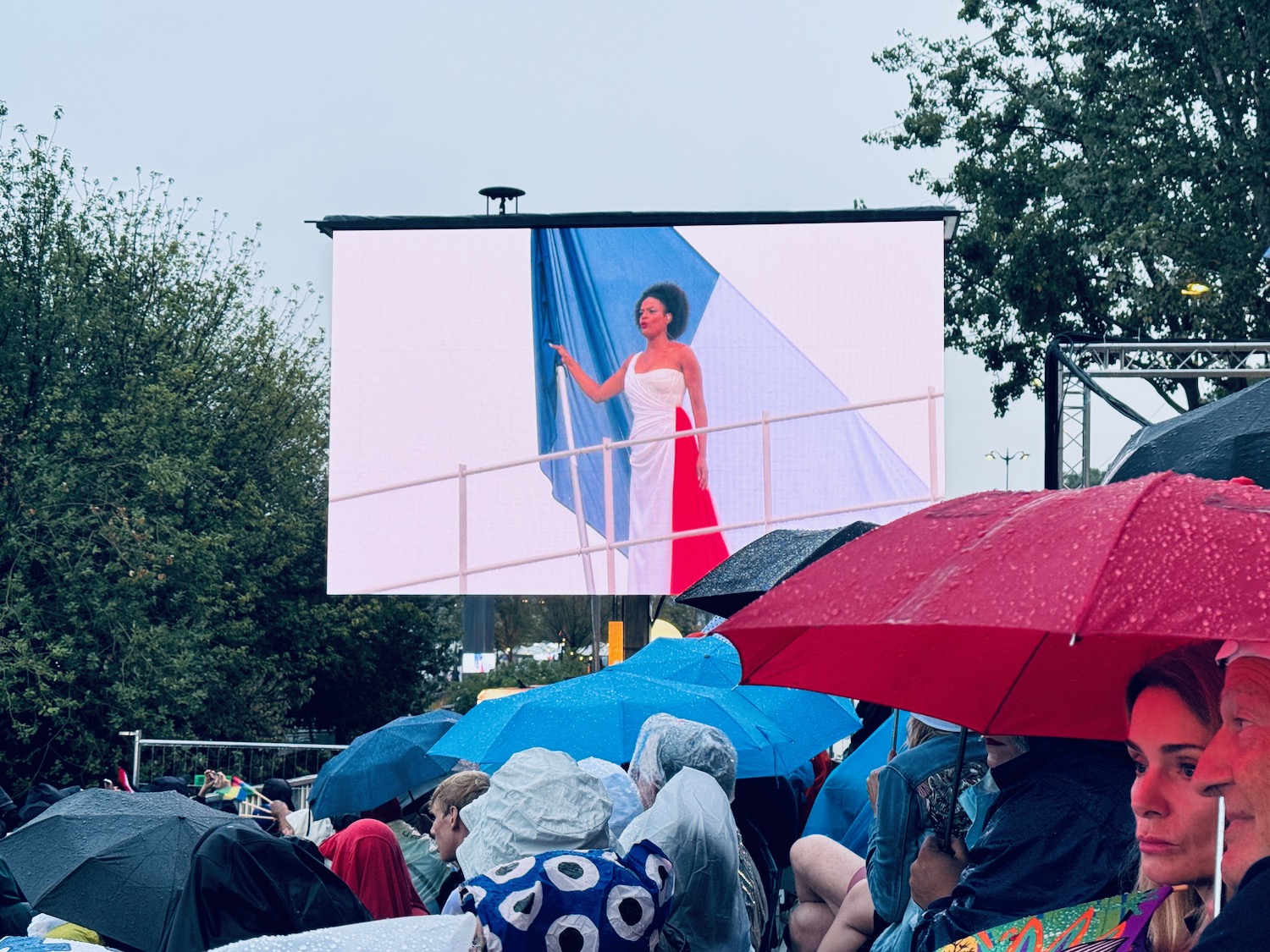 a woman in a white dress standing on a railing with a blue and red flag